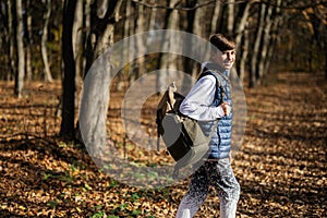 Autumn outdoor portrait of teenager boy with backpack in forest