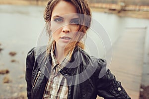 Autumn outdoor portrait of young beautiful woman with natural makeup in leather jacket and plaid shirt