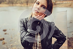 Autumn outdoor portrait of young beautiful woman with natural makeup in leather jacket and plaid shirt