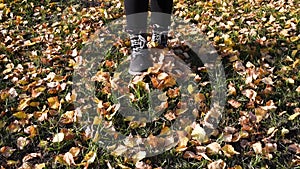 Autumn Park feet in boots toss leaves, running on the grass