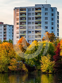 Autumn pattern, city buildings and multicolored trees at lake