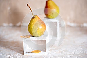 Autumn pear in a white old wooden small box. Life style. Yellow autumn leaves on a concrete light background. Selective focus, spa