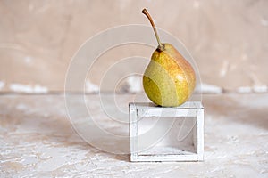Autumn pear in a white old wooden small box. Life style. Yellow autumn leaves on a concrete light background. Selective focus, spa