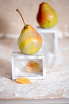 Autumn pear in a white old wooden small box. Life style. Yellow autumn leaves on a concrete light background. Selective focus, spa