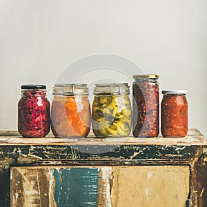 Autumn pickled vegetables in jars placed in line, square crop