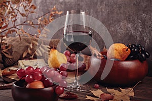 Autumn picnic with wine and cheese platter, fruits and dry leaves