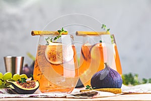 Autumn pink cocktail with fig, thyme, cinnamon and grapes in glass on pink concrete background, close up