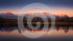 Autumn pond with the reflection of the mountains on the surface at sunset