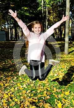 Autumn portrait of adorable happy jumping little girl child