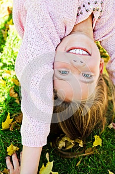 Autumn portrait of adorable smiling little girl child standing upside down on grass and having fun