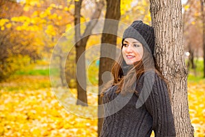 Autumn portrait of beautiful woman over yellow leaves while walking in the park in fall. Positive emotions and happiness concept.