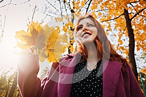 Autumn portrait of candid beautiful red-haired girl with fall leaves in hair.