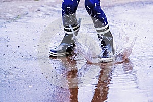 Autumn portrait of child girl jumping in puddles after rain. Huppy childhood, laisure concept