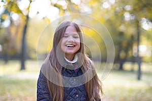 Autumn portrait of cute little blond girl in city park. Beautiful laughing child having fun outdoors on a warm fall day