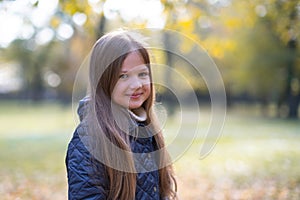 Autumn portrait of cute little blond girl in city park. Beautiful smiling child having fun outdoors on a warm fall day