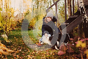 Autumn portrait of happy kid girl playing with her spaniel dog