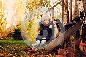 Autumn portrait of happy kid girl playing with her spaniel dog in the garden