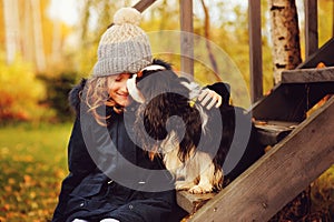 Autumn portrait of happy kid girl playing with her spaniel dog in the garden