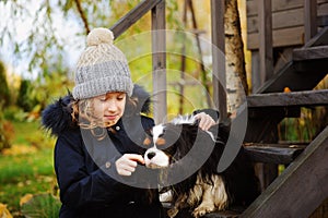 Autumn portrait of happy kid girl playing with her spaniel dog in the garden