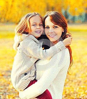 Autumn portrait of happy smiling mother with her daughter child in the park