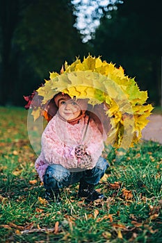 Autumn portrait of little girl with umbrella covered with yellow maple leaves