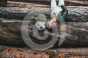 Autumn portrait of mother and little girl kissing on stack of logs