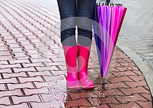 Autumn. Protection in the rain. Woman (girl) wearing pink rubber boots and has colorful umbrella.