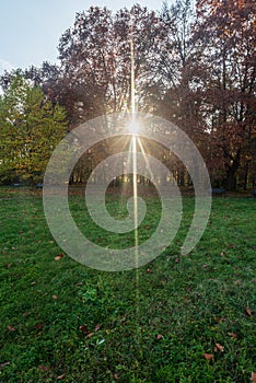 Autumn public park with meadow, colorful trees and sunlights