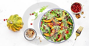 Autumn pumpkin salad with baked honey pumpkin slices, lettuce, arugula, pomegranate seeds and walnuts. Healthy vegan eating,