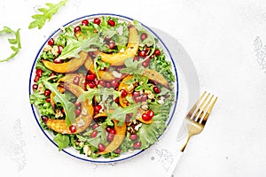 Autumn pumpkin salad with baked honey pumpkin slices, lettuce, arugula, pomegranate seeds and walnuts. Healthy vegan eating,