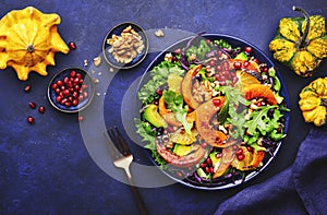 Autumn pumpkin salad with caramelized pumpkin slices, red cabbage, avocado, arugula, pomegranate seeds and walnuts. Healthy vegan