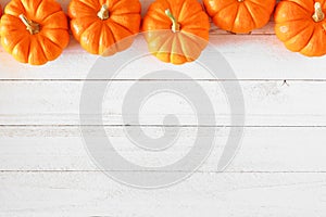Autumn pumpkin top border over a white wood background