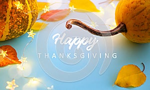 Autumn pumpkins and yellow autumn leaves on light blue background as decorations for thanksgiving day; thanksgiving banner with