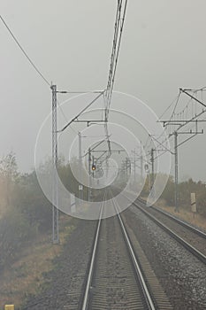 Autumn railway tracks and traffic signals in a foggy morning. View from the last car of the train. Tourism concept.