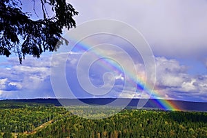 Autumn rainbow over the Usva River near the Usvinskie Stolby stone after a charge of snow grains