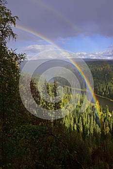 Autumn rainbow over the Usva River near the Usvinskie Stolby stone after a charge of snow grains
