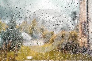 autumn rainy view from the window, raindrops on glass, blurred cloudy rainy sky background