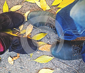 Autumn romance. Legs of man and woman on fallen leaves