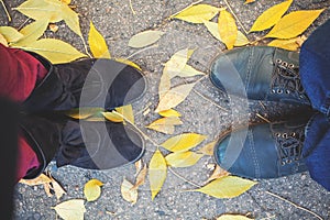 Autumn romance. Legs of man and woman on fallen leaves