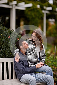 Autumn Romance: Young Couple Embracing and Kissing on Park Bench. Young couple kissing and rejoices at the lake