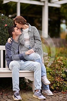 Autumn Romance: Young Couple Embracing and Kissing on Park Bench. Young couple kissing and rejoices at the lake