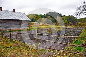 Autumn rural landscape with fence, field, forest and house