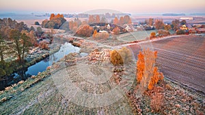 Autumn rural landscape. Frost on grass. River, field, meadow, village, fall color trees
