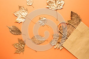 Autumn sale. Gold leaves in a bag on an orange background