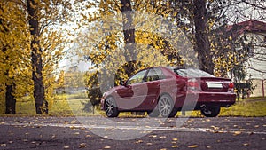 Autumn scene with Cherry red 4 door family d-class sedan Toyota Camry