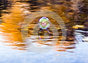 Autumn scene at a river with clear water and reflection of a soap bubble