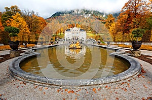 Autumn scenery of Linderhof Palace in Bavaria Germany, with view of a golden statue in the circular fountain pond