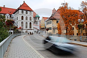 Autumn scenery at a street corner in the Old Town of Fussen, with a car driving on a bridge
