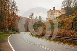 Autumn scenery of winding road, colorful trees and Pieskowa Skala castle in Ojcow National Park, Poland