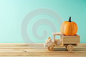 Autumn season concept with toy truck and glitter pumpkin decor on wooden table